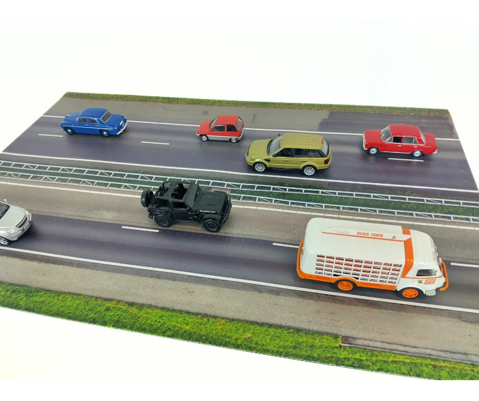 Model cars on a miniature road with green grass and white background