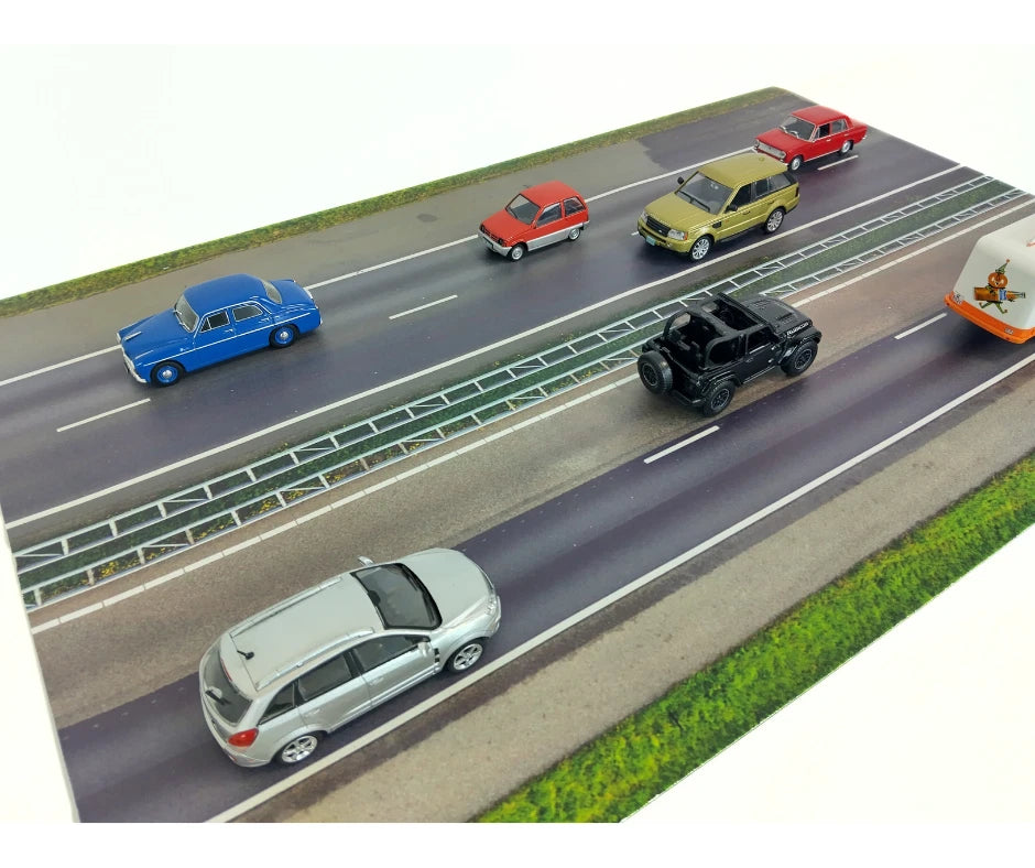 Model cars on a miniature road with different vehicles including a blue car, red car, yellow car, black car, and white car.